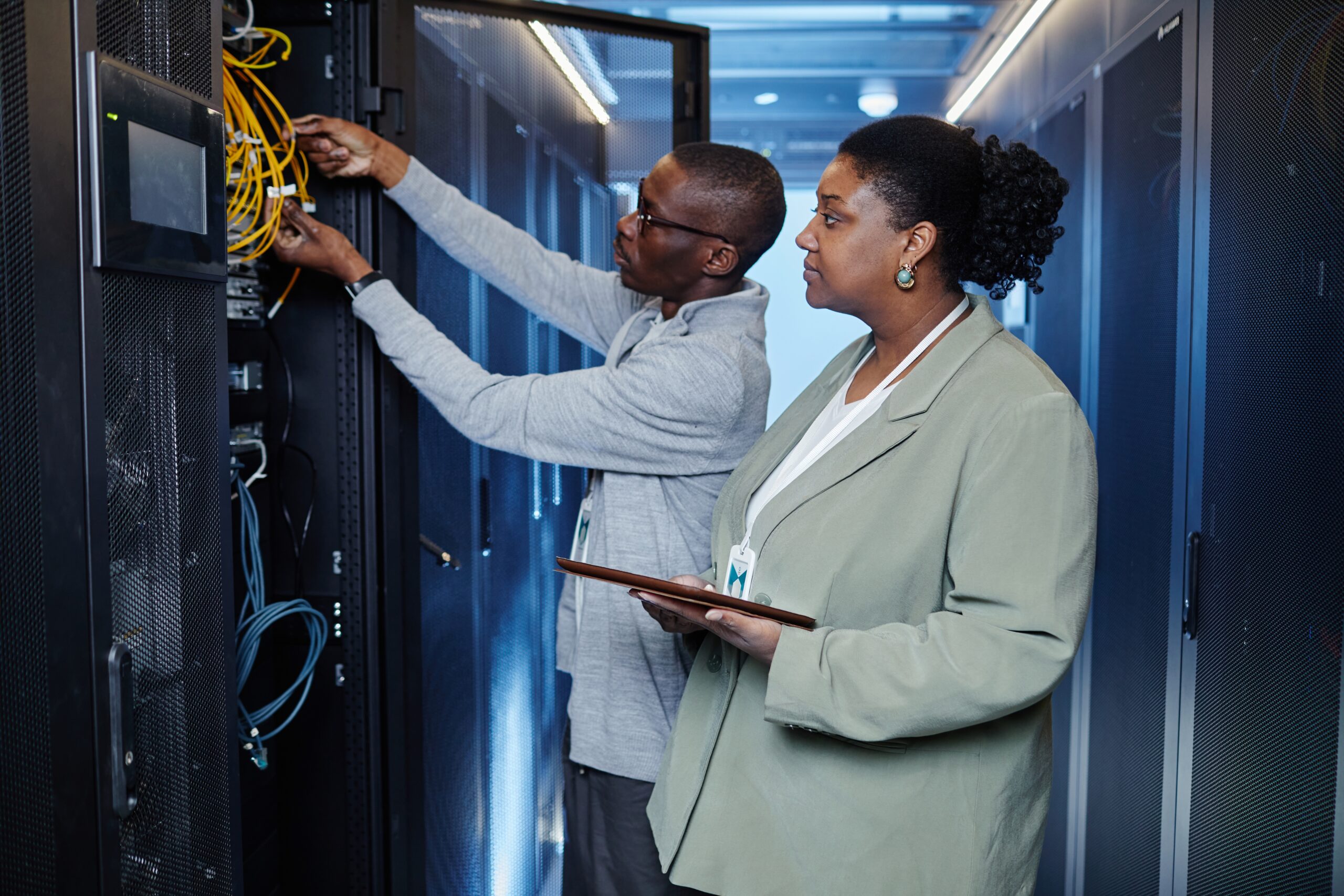 Waist,Up,Portrait,Of,Two,System,Managers,Inspecting,Server,Cabinets